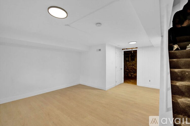 A room with wooden flooring and a staircase on the right side.