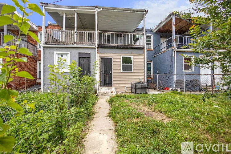 A pathway leads to a two-story house with a balcony.