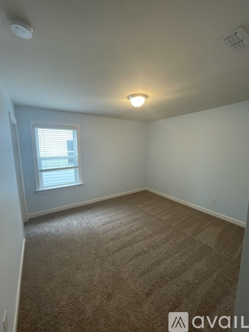 A room with a carpeted floor and a window with blinds.