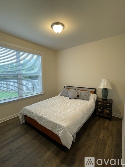 A bedroom with a bed, nightstand, and window.
