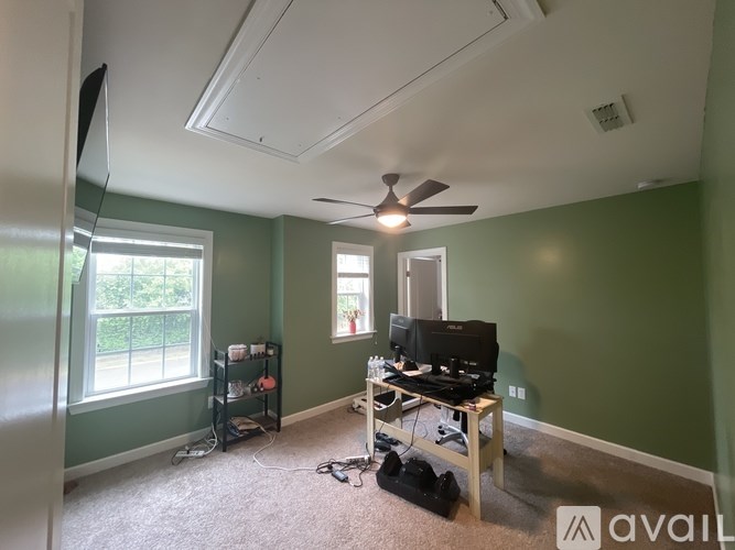 A room with a television, a computer desk, and a window.