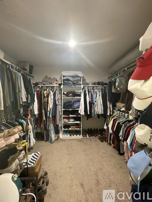 A room full of clothes and a hat on a shelf.
