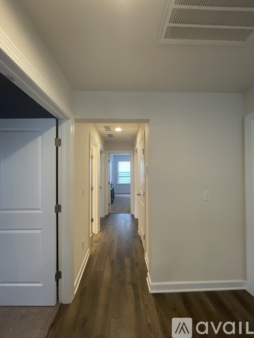 A long hallway with a door on the left and a window in the distance.