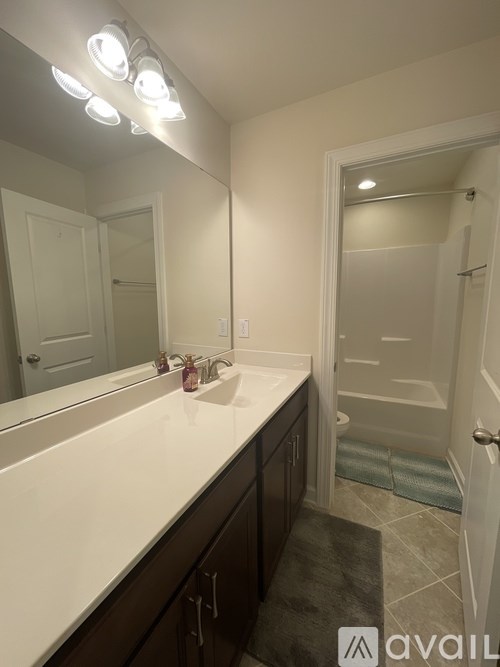 A bathroom with a vanity, mirror, and lights.