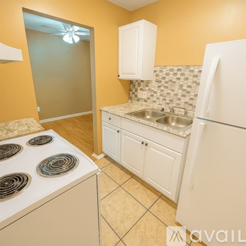 A kitchen with a white fridge, white cabinets, and a white stove top.