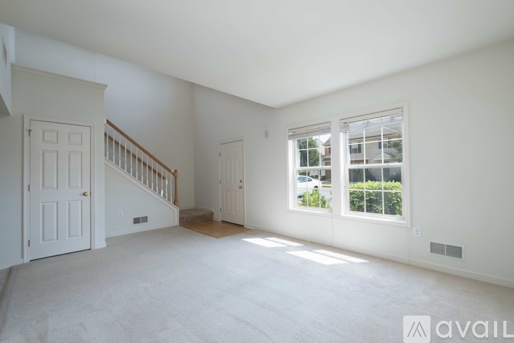 A spacious room with a staircase and a window overlooking a parking lot.