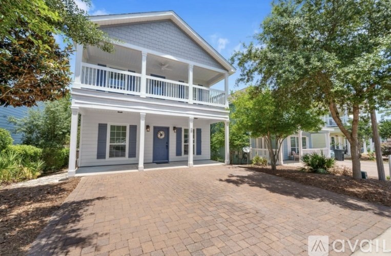 A two-story house with a balcony and a driveway in front.