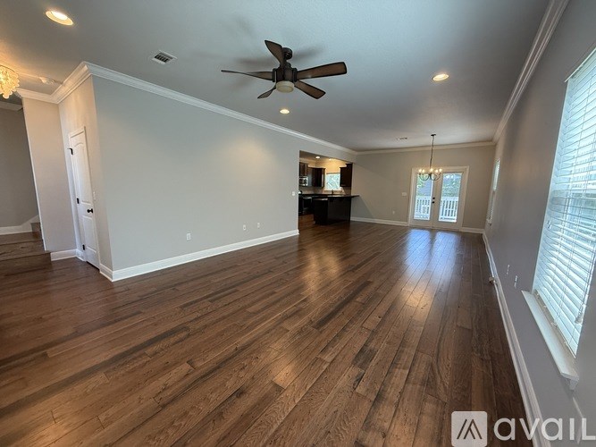A spacious room with wooden floors and a ceiling fan.