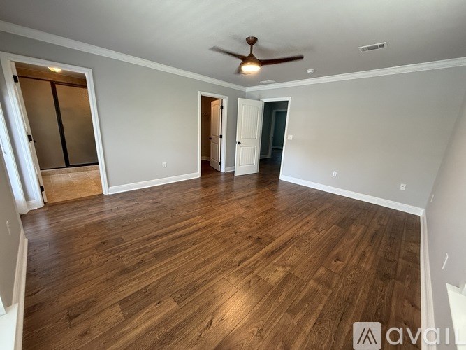 A spacious room with wooden flooring and a ceiling fan.