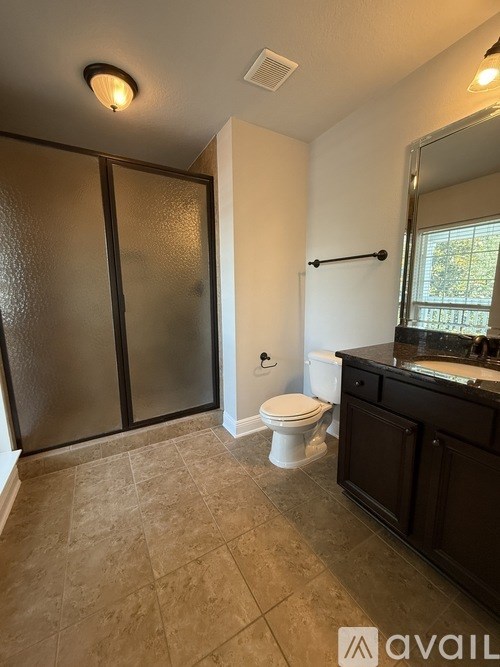 A bathroom with a toilet, sink, and frosted glass shower door.