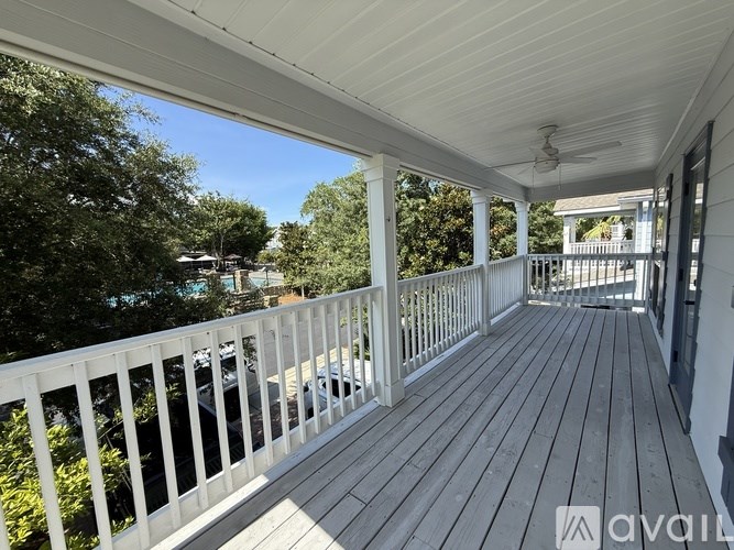 A wooden deck with a white railing and a ceiling fan.