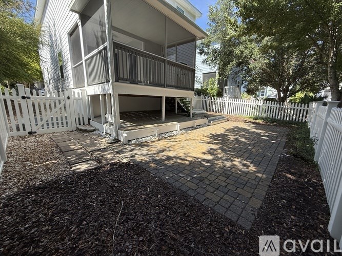 A white fence surrounds a patio with a brick border.