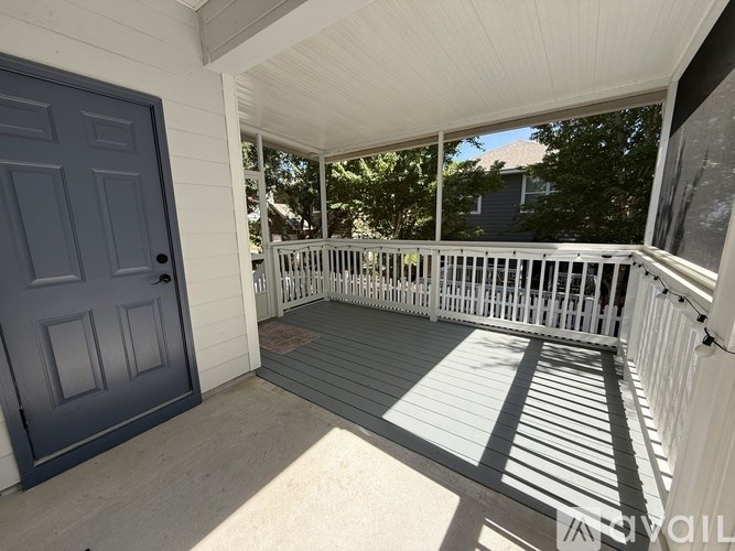 A porch with a white railing and a grey door.