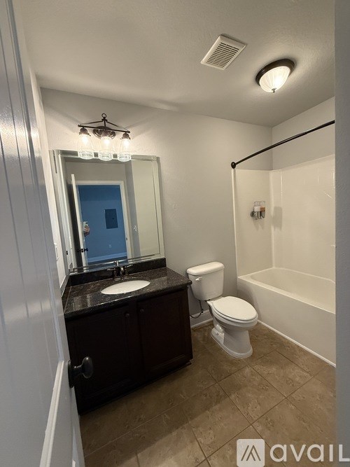 A bathroom with a toilet, sink, and mirror.