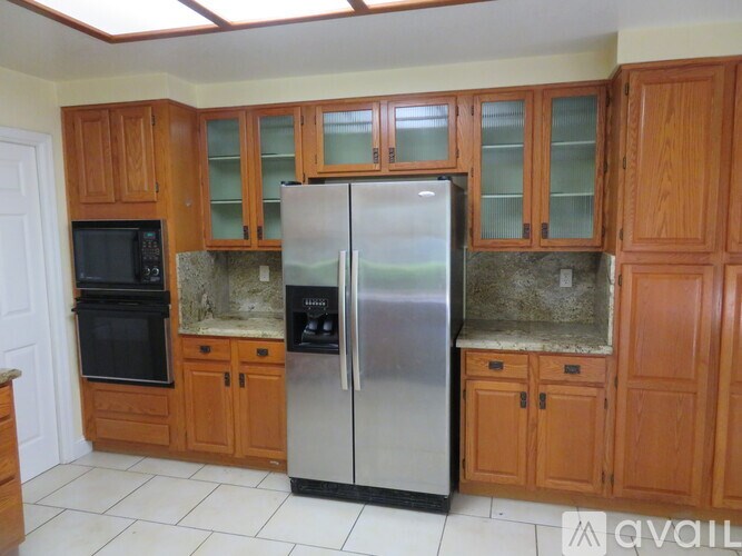 A kitchen with wooden cabinets and a stainless steel refrigerator.