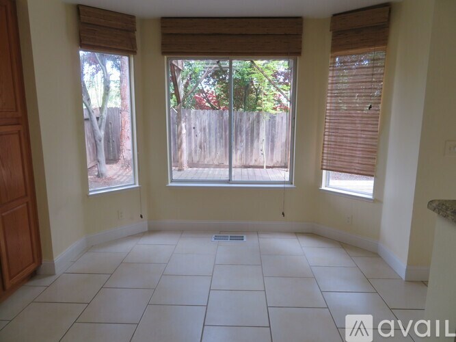 A room with a tiled floor and two windows overlooking a wooden fence.