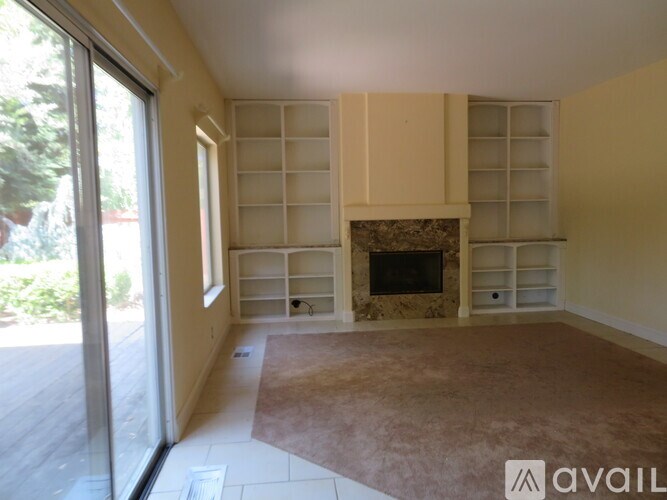 A room with a fireplace and a wall of shelves.
