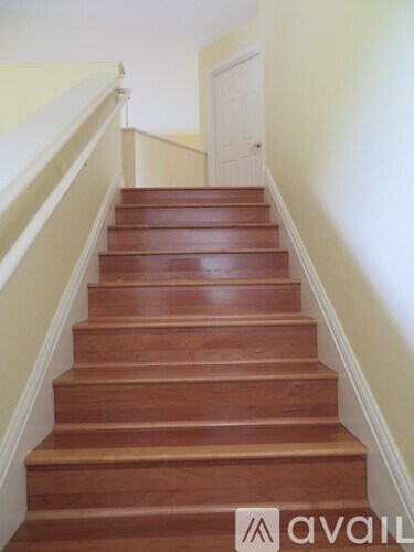 A brown wooden staircase with a white railing.