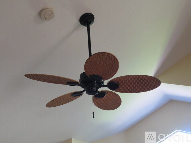 A ceiling fan with brown blades is hanging from the ceiling.