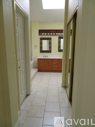 A bathroom with a white tile floor and a wooden vanity.