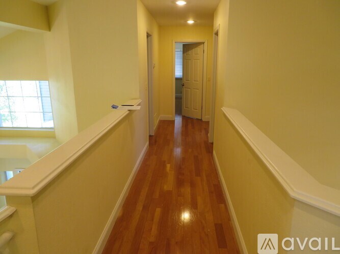 A hallway with wooden floors and white walls.