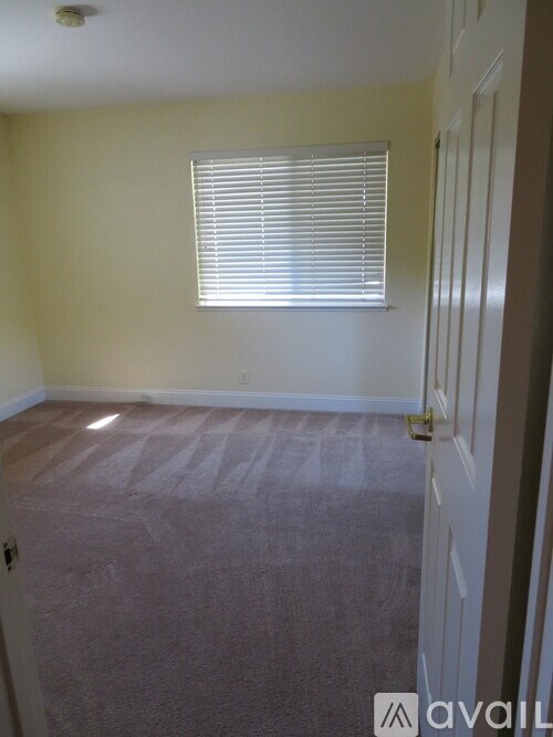 A room with a carpeted floor and a window with blinds.