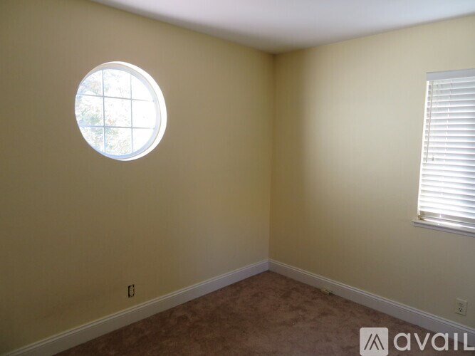 A room with a round window and a carpeted floor.