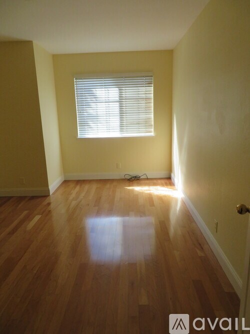 A room with wooden floors and a window with blinds.