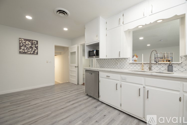 A kitchen with white cabinets and a grey floor.