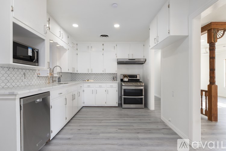 A kitchen with white cabinets and a grey floor.