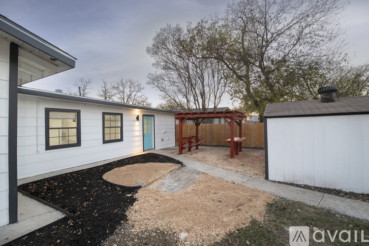 A backyard with a white fence and a red bench.