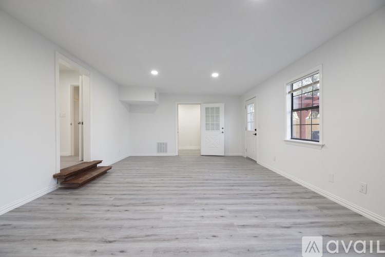 A spacious room with wooden flooring and white walls.