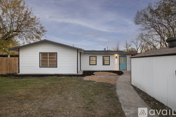 A white house with a blue door is surrounded by a grassy area.