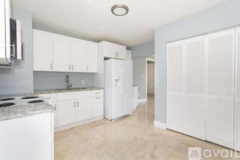 A kitchen with white cabinets and a white refrigerator.