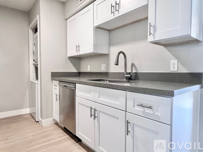 A kitchen with white cabinets and a black countertop.