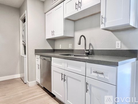 A kitchen with white cabinets and a black countertop.