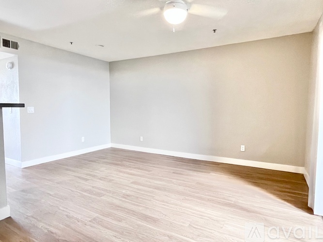 A spacious room with light wood flooring and white walls.