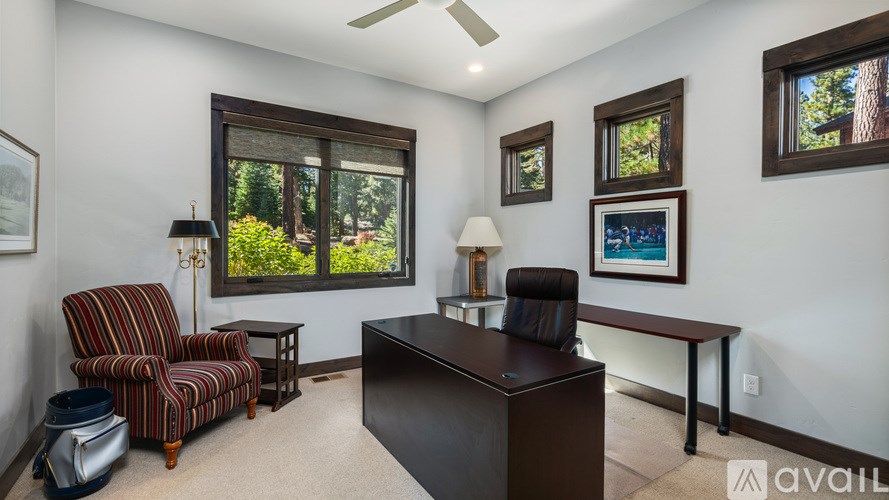 A room with a striped chair, a desk, and a ceiling fan.