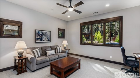 A living room with a grey couch, a wooden coffee table, and a ceiling fan.