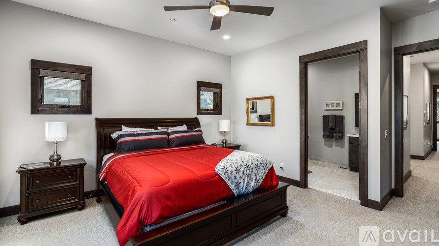 A bedroom with a red bedspread and a ceiling fan.