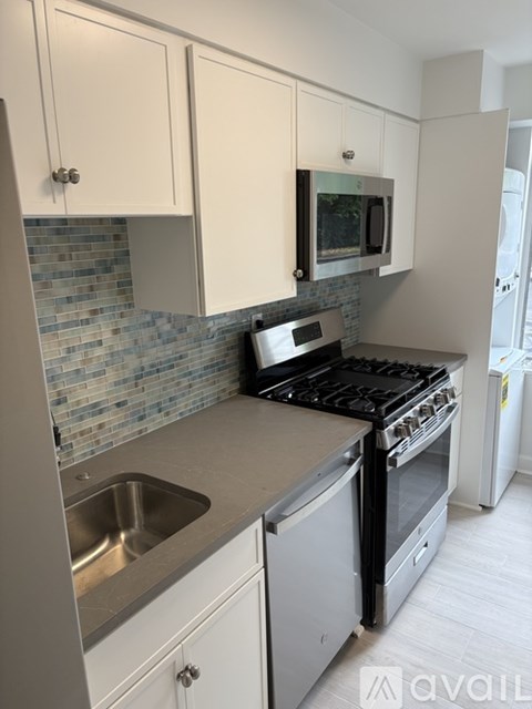 A kitchen with a stove, sink, and cabinets.