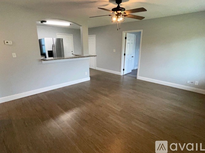 A spacious room with a ceiling fan and wooden flooring.
