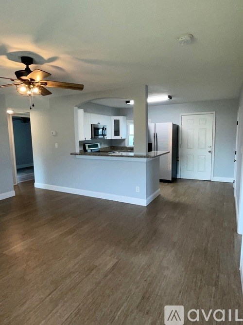 A living room with a ceiling fan and hardwood floors.