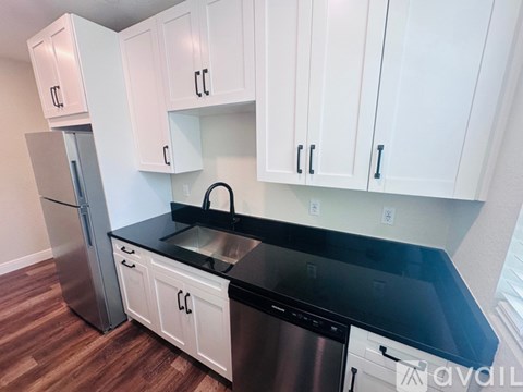 A kitchen with white cabinets and a black countertop.