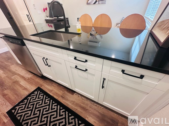 A kitchen with white cabinets and a black countertop.