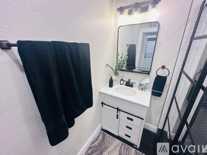 A black towel is hanging on a hook in a bathroom.