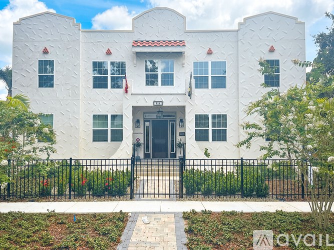 A white building with a black fence in front.