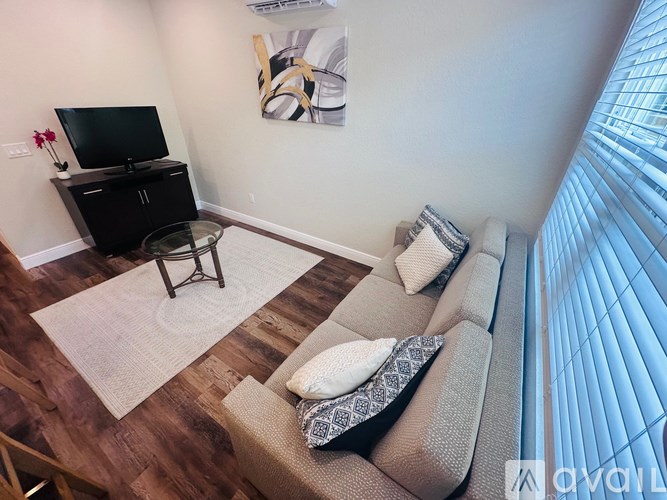 A living room with a grey couch, a black cabinet, and a television.