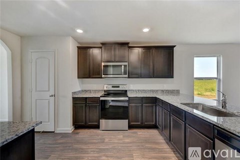 A kitchen with dark brown cabinets and a granite countertop.