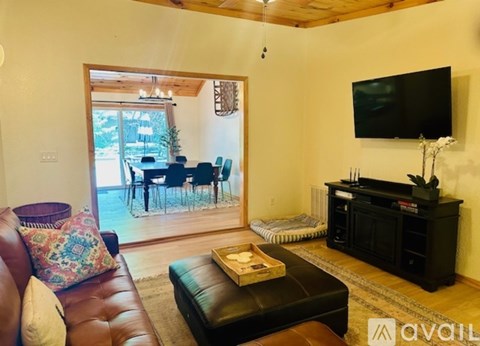 A living room with a brown leather couch and a flat screen TV mounted on the wall.